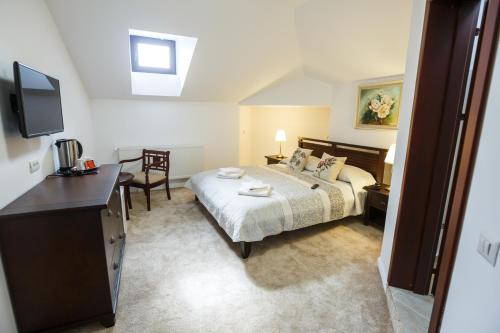 a bedroom with a bed and a desk and a television at Maisonette Apartments in Cîmpulung