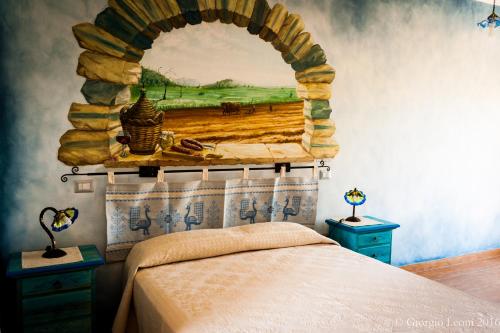 a bedroom with a bed with a painting on the wall at Agriturismo Le Vigne Ducali in Màndas