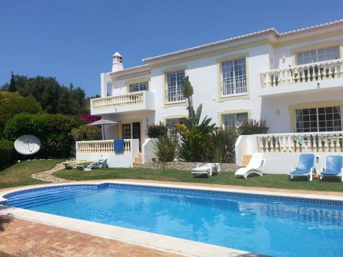 a villa with a swimming pool in front of a house at Praia da Luz Apartments in Luz