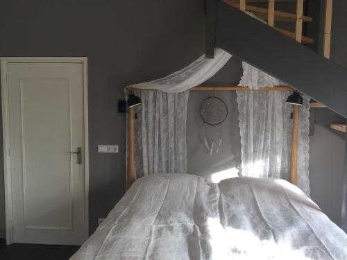 1 dormitorio con 1 cama con dosel y reloj en la pared en Boerengastenverblijf De Kromme Rijn, en Cothen