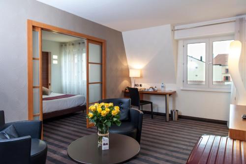ベルフォールにあるBrit Hotel Belfort Centre-Le Borealのリビングルーム付きのスイートを備えたホテルルームです。