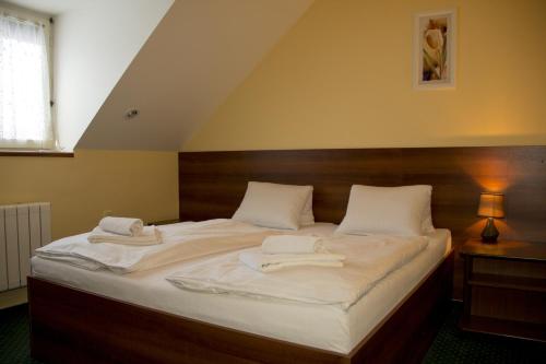 a large bed with two white towels on it at Penzion Oaza in Luhačovice