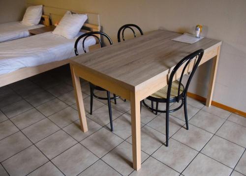 a wooden table and chairs in a room with a bed at Condo Gardens Antwerp in Antwerp