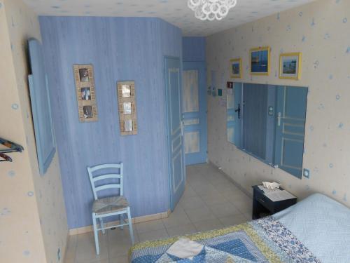 Saint-Laurent-de-la-PréeにあるLa Roche bleueの青い壁のベッドルーム1室、椅子、ベッド1台が備わります。
