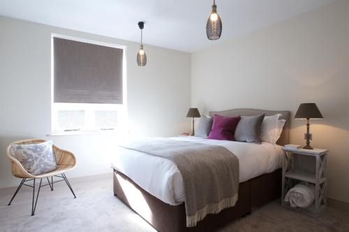 a bedroom with a bed and a chair and a window at Kings Head in Cirencester