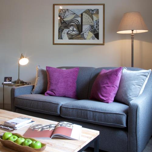 a living room with a blue couch and purple pillows at Kings Head in Cirencester
