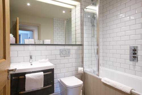 a bathroom with a sink and a toilet and a tub at Kings Head Hotel in Cirencester