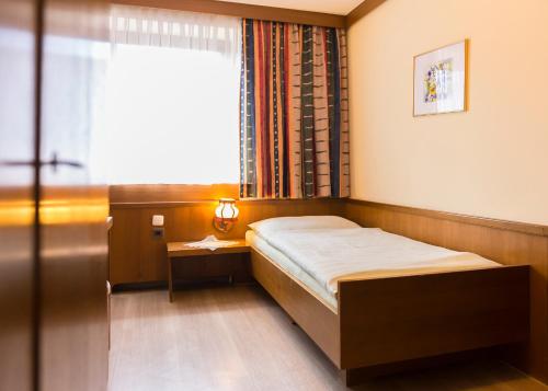 a small bedroom with a bed and a window at Gasthof Mandorfer in Hörsching