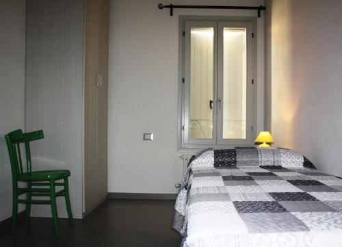 a bedroom with a bed and a green chair at Appartamento Borghetto in Comacchio