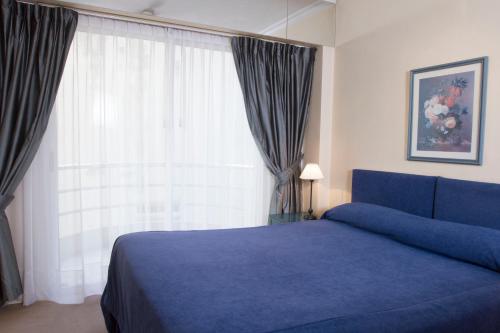 a bedroom with a blue bed and a large window at Mayla Apartments in Buenos Aires