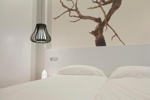 a bedroom with a white bed with a tree on the wall at Khu Hotel in Granada