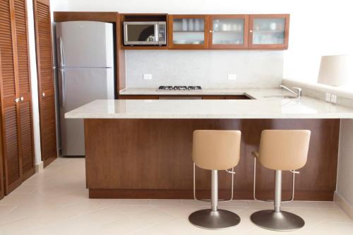 a kitchen with a refrigerator and two bar stools at Las Villas Akumal in Akumal