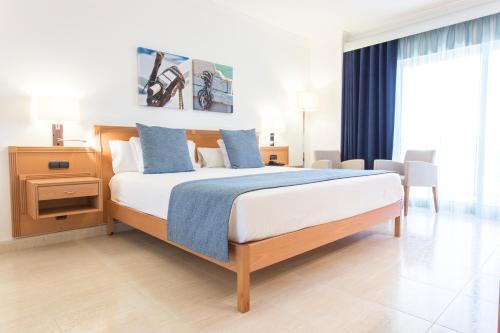 a bedroom with a large bed with blue pillows at Ukino Palmeiras Village - 24h All Inclusive in Armação de Pêra
