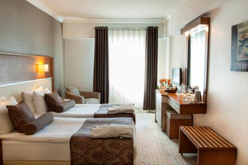 a hotel room with two beds and a desk at Blanca Hotel in İzmir