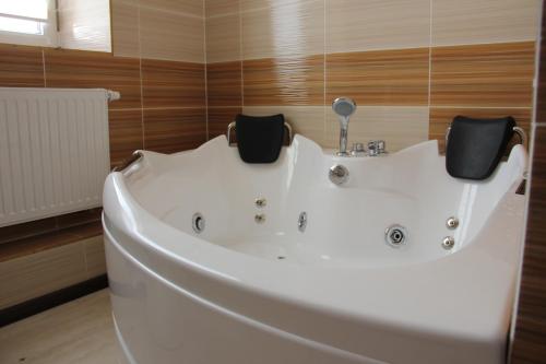 un bagno con vasca bianca e pareti in legno di MishyN-City Hotel a Dobrowlany