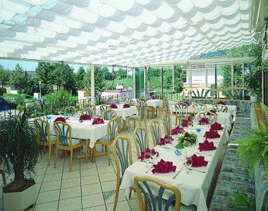 un grupo de mesas y sillas con flores rojas. en Hotel Bayerischer Hof Rehlings, en Weißensberg