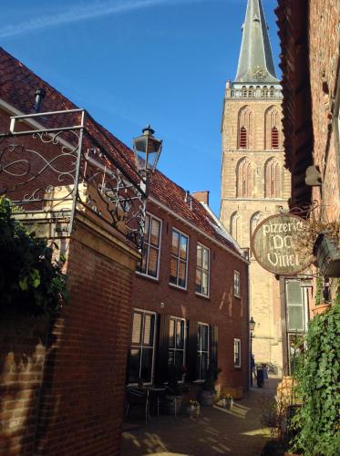 a church with a tower and a building with a sign at Hart van Lochem in Lochem