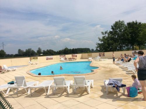 una piscina con sillas y gente sentada a su alrededor en Camping du RIED en Boofzheim