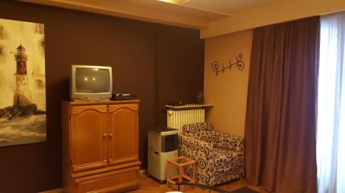 a living room with a tv on a cabinet and a chair at Hospitality Centrum- River in Bucharest