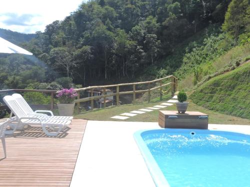 einen Pool auf einer Holzterrasse mit einem Stuhl und einem Tisch in der Unterkunft Sitio Da Cachoeirinha Paraju Domingos Martins in Floriano Simmer