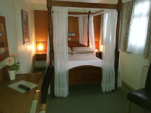 1 dormitorio con cama con dosel y cortinas blancas en Mornington Hotel en Saint Helier