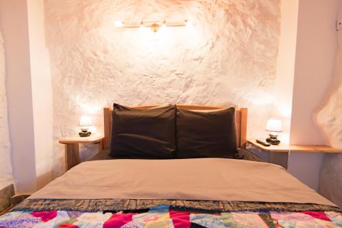 1 dormitorio con 1 cama con pared blanca en Stone Dreams - Namoradeira en Calheta de Nesquim