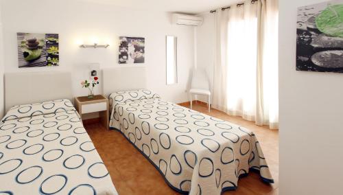 1 dormitorio con 2 camas y ventana en Typic Sandic Apartments en Es Cana