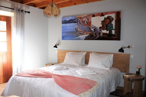 um quarto com uma cama branca e uma pintura na parede em Pico Formoso Vínea Lava Alojamentos Pico em Prainha de Baixo