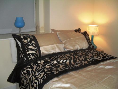 a bed with a black and white blanket and a lamp at corwen holiday apartment in Llandudno