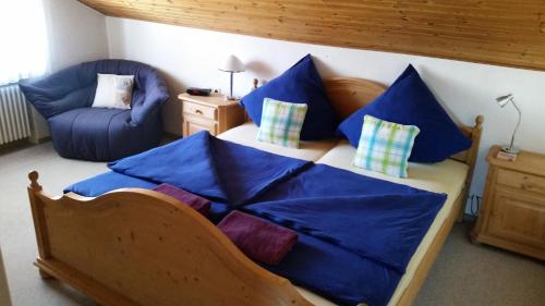 Schlafzimmer mit einem Bett mit blauer Bettwäsche und einem Stuhl in der Unterkunft Ferienwohnung Johanna in Schwangau