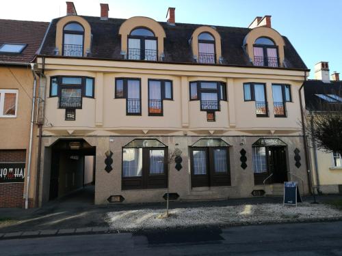 - un grand bâtiment avec des portes et des fenêtres noires dans l'établissement Mátyás Szállás Panzió, à Szombathely