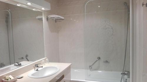 a bathroom with a sink and a shower at Logis Au Grand Hotel et son restaurant in Mayenne