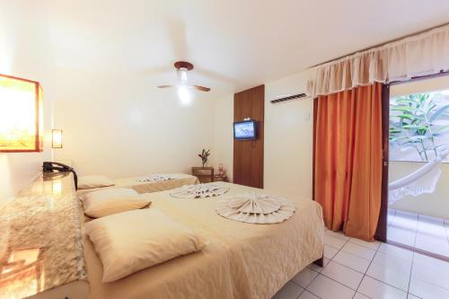 a hotel room with two beds and a television at Rede Andrade Terra Brasil in Porto Seguro