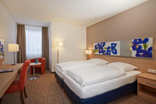 ニーダーンハウゼンにあるH+ Hotel Wiesbaden Niedernhausenの大型ベッド、デスク、デスクが備わる客室です。