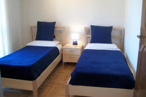 two beds with blue sheets in a small room at B&B SouthItaly in Busto Arsizio