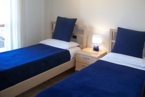 a bedroom with two beds with blue sheets and a lamp at B&B SouthItaly in Busto Arsizio