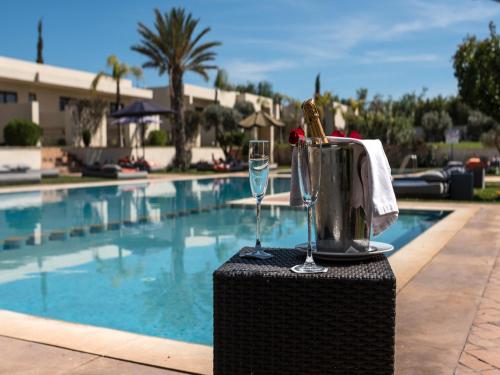 a table with a glass of wine next to a swimming pool at Sirayane Boutique Hotel & Spa Marrakech in Marrakesh