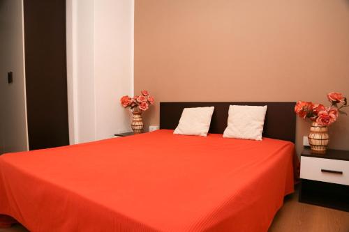 a bedroom with a red bed with two vases with flowers at Casa Bea in Quartu SantʼElena