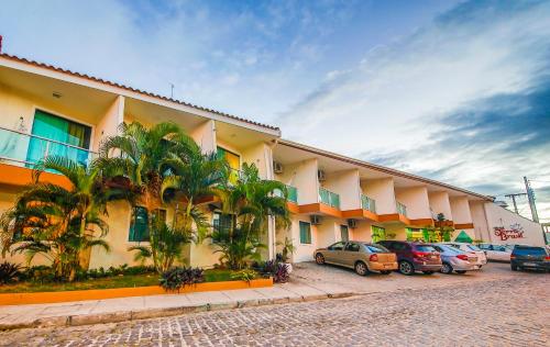 a hotel with cars parked in a parking lot at Terra Brasil - Rede Soberano in Porto Seguro