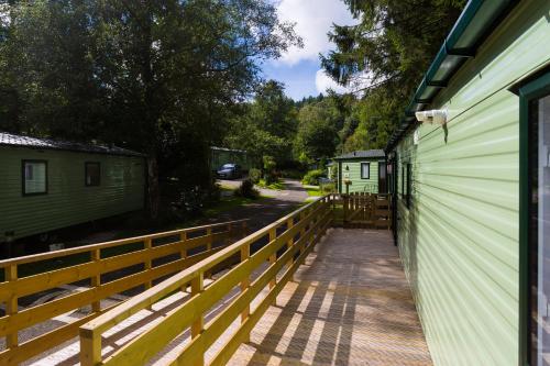 a wooden walkway next to a green building at Newby Bridge Country Caravan Park in Newby Bridge