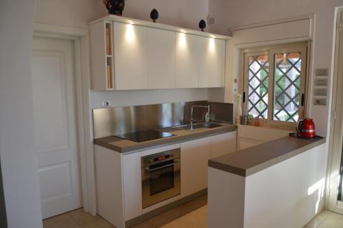 a kitchen with white cabinets and a sink and a stove at Villa Paola in Fontane Bianche