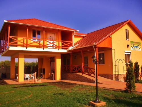 a house with a porch and a balcony at Tó- Party Panoráma Panzió & Wellness in Kiszombor