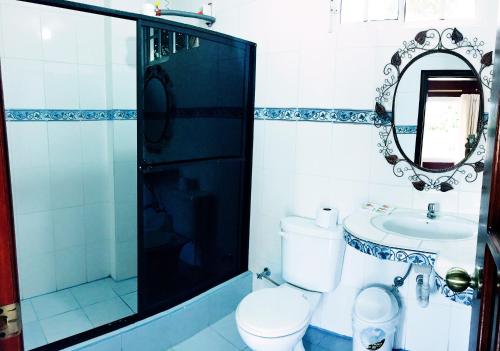 een badkamer met een toilet, een wastafel en een spiegel bij Hosteria Don Elias in Puyo