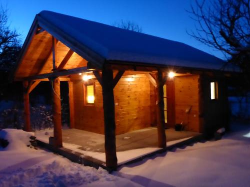 a wooden cabin with a blue roof in the snow at Zergeboglár Vendégház in Szilvásvárad