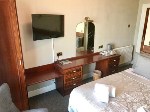a bedroom with a desk with a television and a bed at Bromwell Court in Llandudno