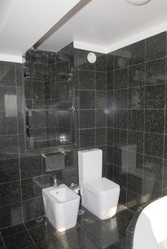 a black tiled bathroom with a toilet and a sink at Porto Sea Apartments in Matosinhos