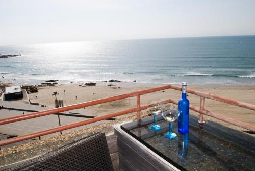 a table with a bottle and two glasses on the beach at Porto Sea Apartments in Matosinhos