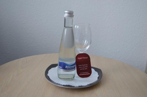 une bouteille sur une assiette à côté d'un verre dans l'établissement Apart' Hotel, à Kehl