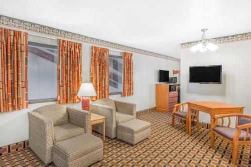 a hotel room with chairs and a table and a television at Super 8 by Wyndham Grants Pass in Grants Pass