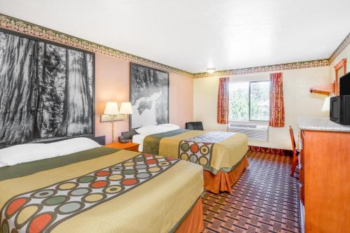 a hotel room with two beds and a television at Super 8 by Wyndham Grants Pass in Grants Pass